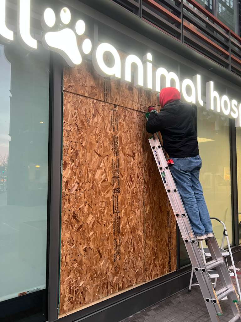 Technician installing emergency board-up on storefront window